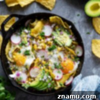 Classic Chilaquiles Verdes with crispy corn chips, homemade salsa verde, charred sweet corn, fried eggs, and an array of fresh toppings.