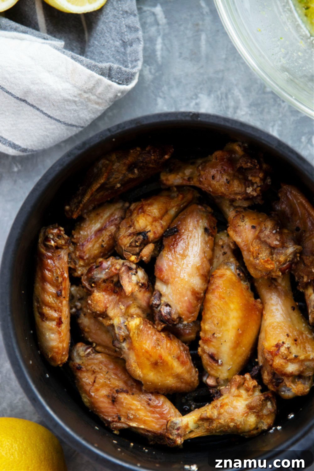 Crispy Air Fryer Lemon Garlic Wings 5 Crispy lemon garlic chicken wings being tossed in a bowl with the delicious butter sauce.