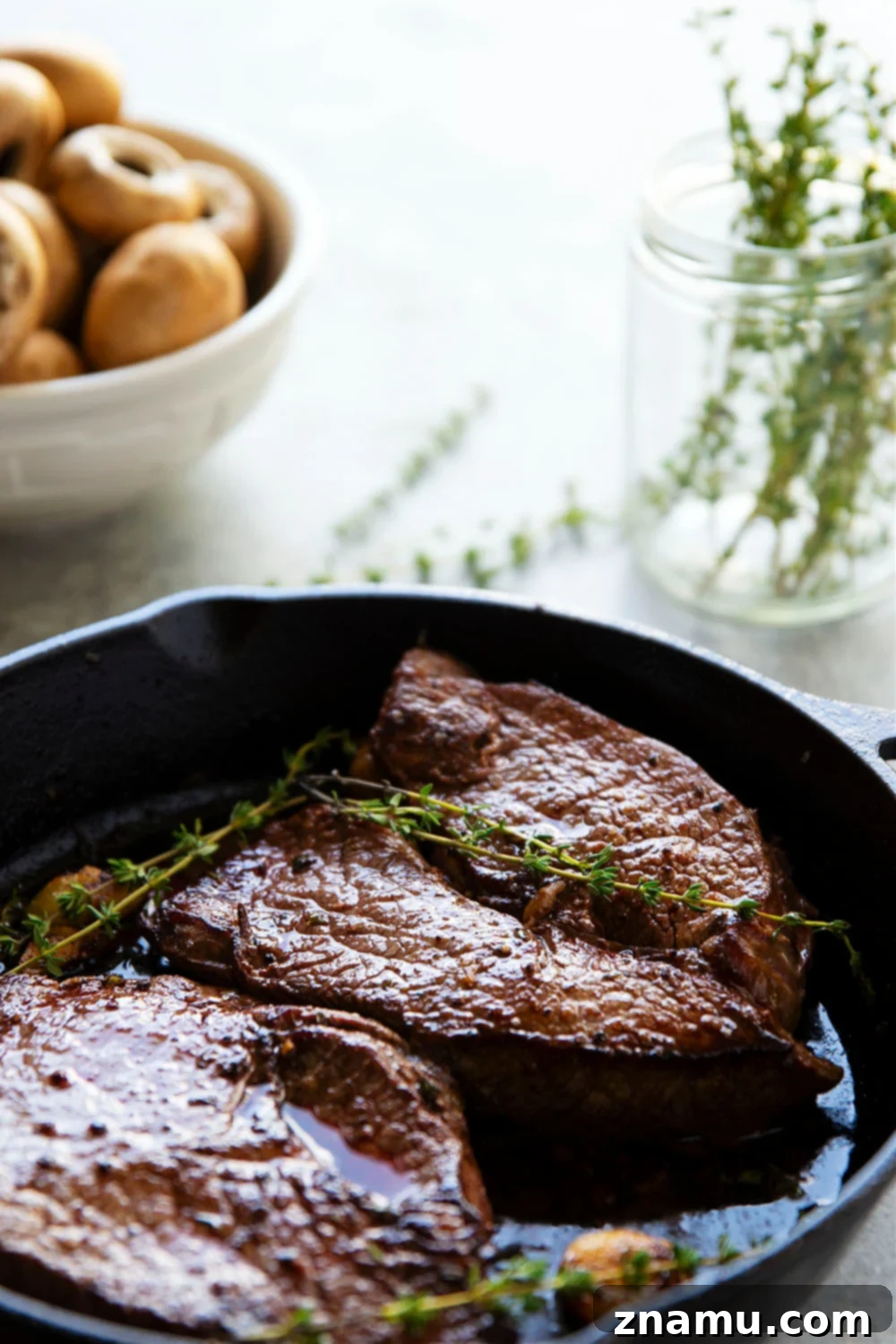 Close-up of seared balsamic glazed steak and golden brown mushrooms in a cast iron skillet.