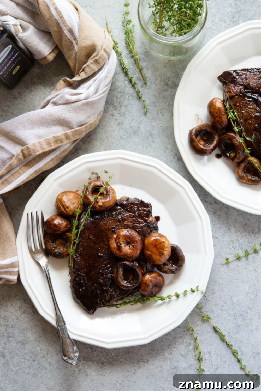 Ingredients for balsamic glazed steak and mushrooms laid out, including sirloin steaks, mushrooms, herbs, and balsamic vinegar.