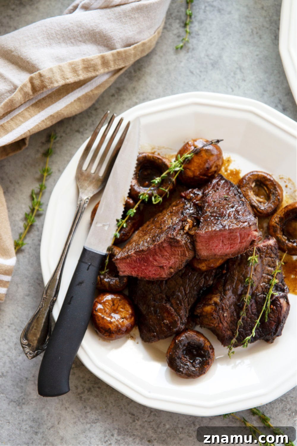 Skillet balsamic glazed steak and mushrooms garnished with fresh thyme, ready to serve.