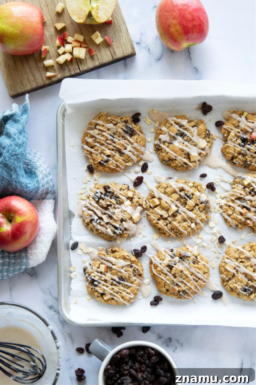 Sweetly Glazed Apple & Raisin Oatmeal Cookies 5 Ingredients for Oatmeal Raisin Apple Cookies laid out, including fresh apples and oats.