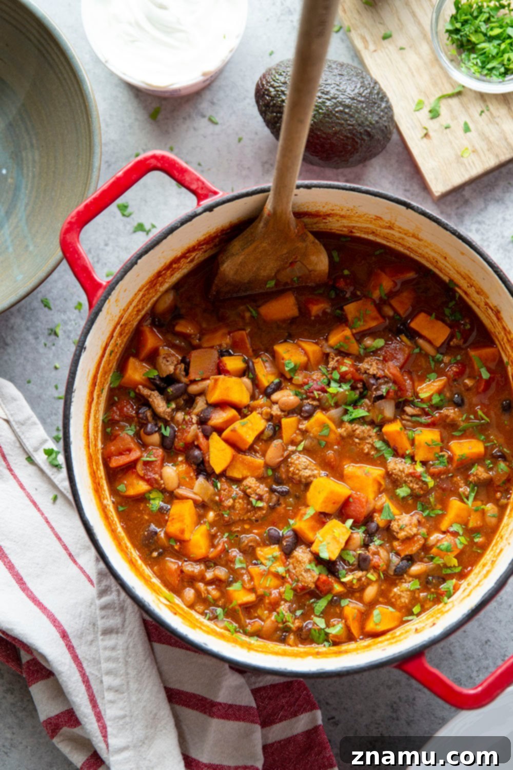 Bold Chipotle Chicken Sweet Potato Chili 2 A vibrant bowl of Chipotle Chicken Sweet Potato Chili, garnished with sour cream and fresh cilantro, promising smoky and sweet flavors in a hearty, one-pot meal.