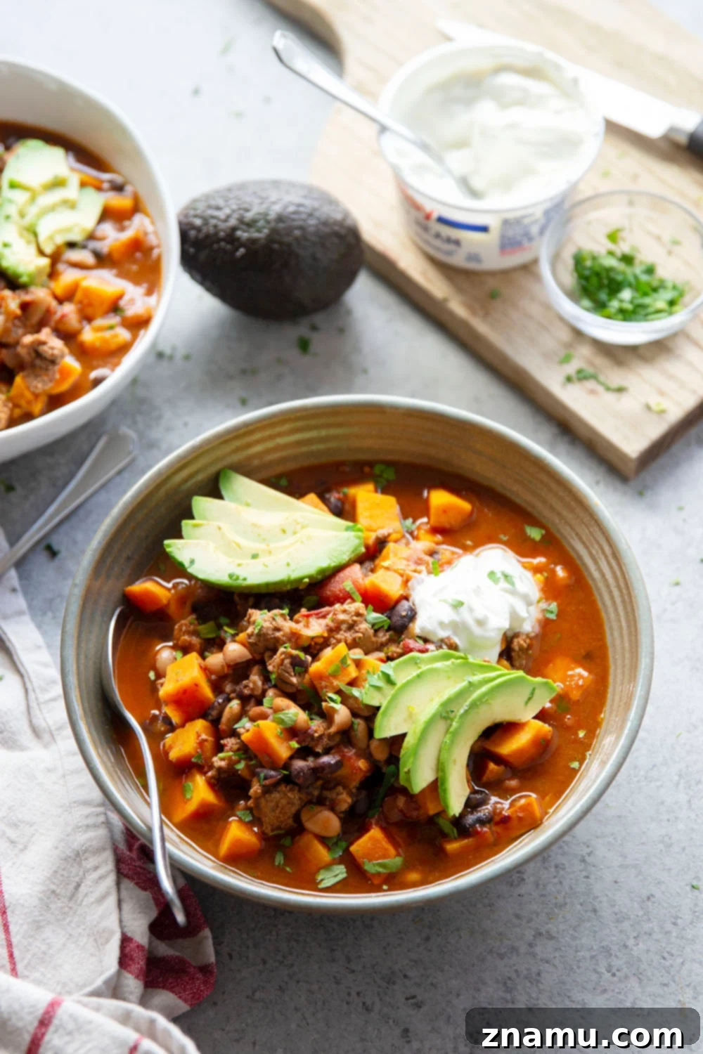 Bold Chipotle Chicken Sweet Potato Chili 3 Close-up of the rich, thick texture of Chipotle Chicken Sweet Potato Chili, showing chunks of sweet potato, ground chicken, and beans in a savory broth.