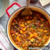 A vibrant bowl of Chipotle Chicken Sweet Potato Chili, garnished with sour cream and fresh cilantro, promising smoky and sweet flavors in a hearty, one-pot meal.