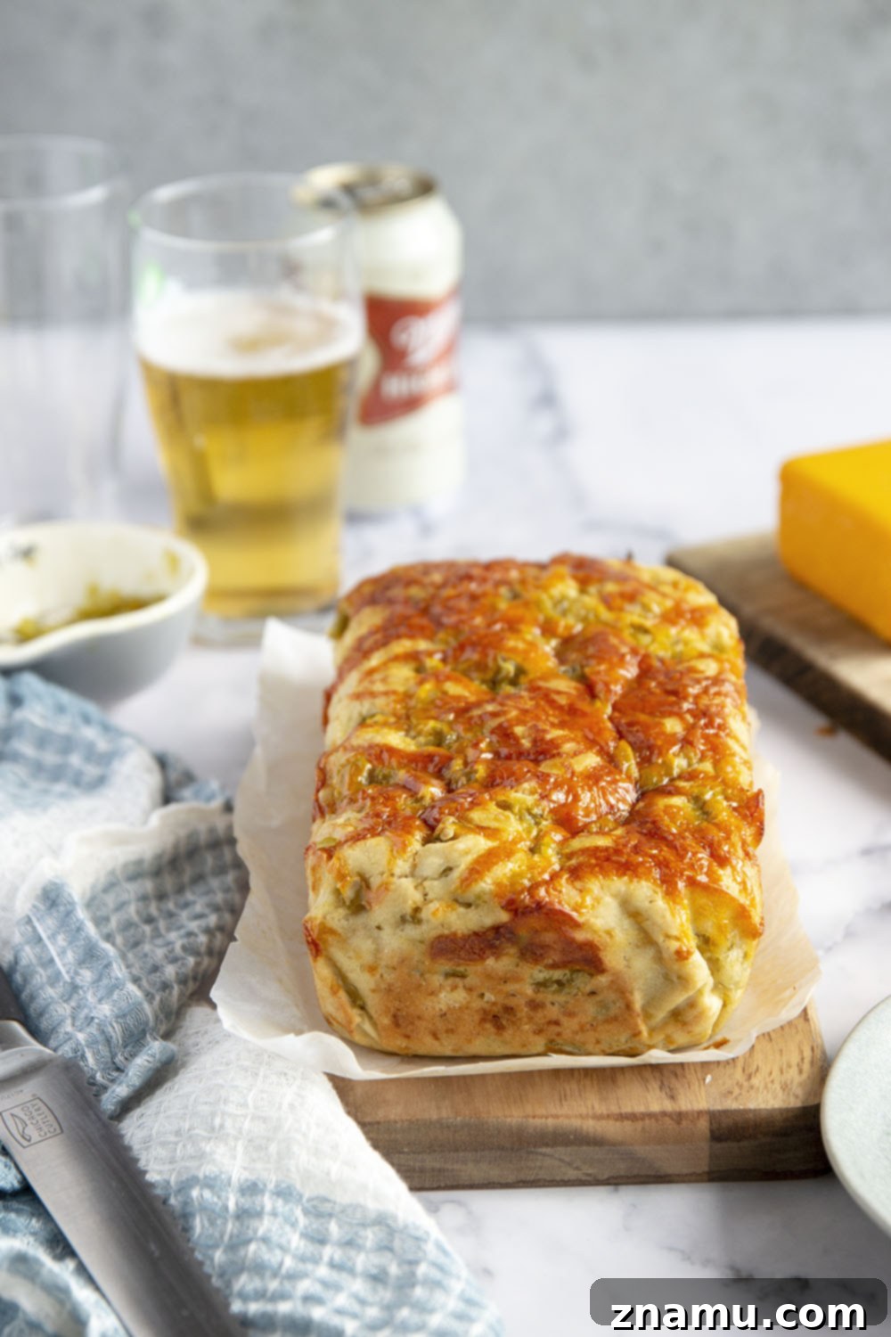 Green Chile Cheddar Ale Loaf 3 Close-up of a slice of Green Chile Cheddar Beer Bread, showing the moist texture, pockets of melted cheese, and chopped green chiles.