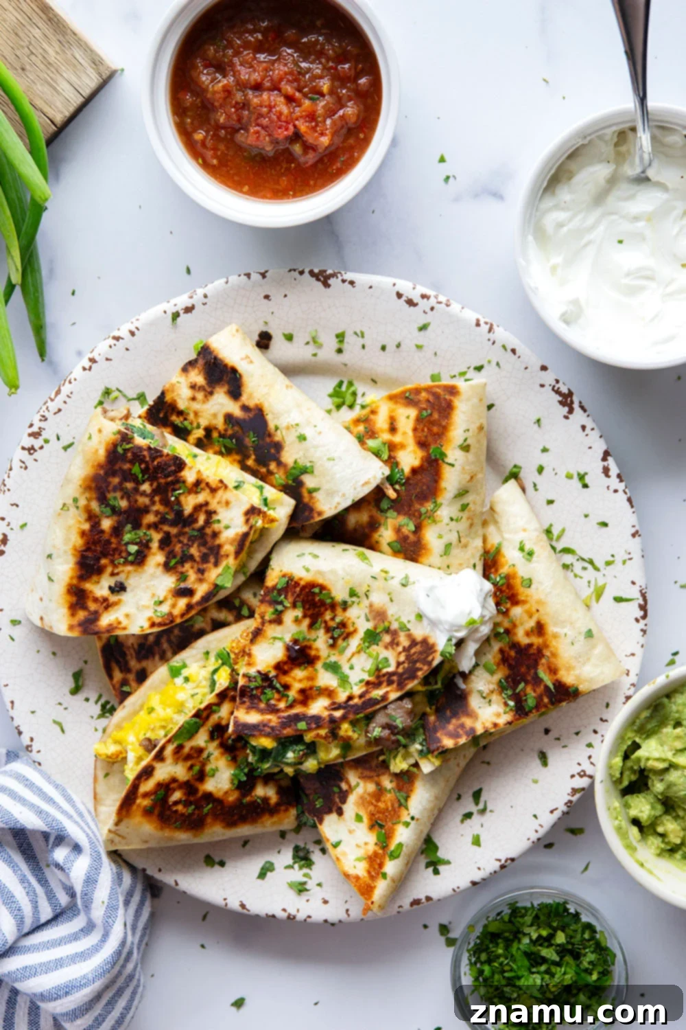 Wholesome Breakfast Quesadillas 4 Plated crispy breakfast quesadillas, cut into wedges, revealing the savory filling of eggs, sausage, and spinach, with fresh cilantro garnish, ready to be enjoyed with dipping sauces.