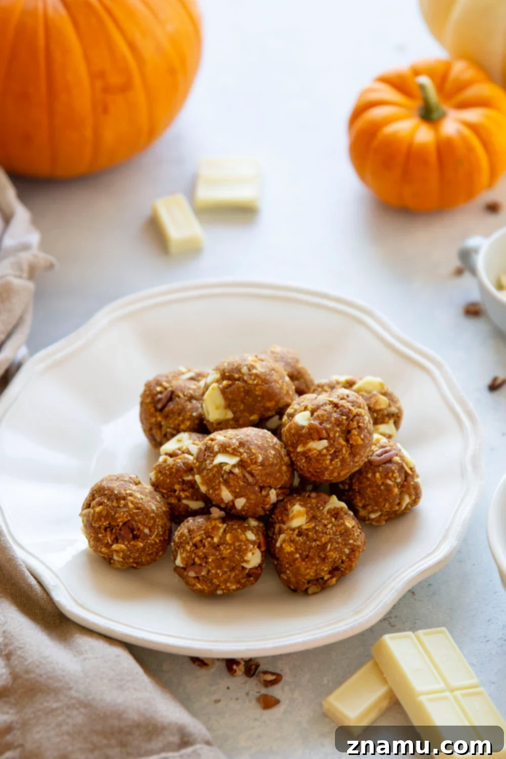 Pumpkin Spice Energy Gems 6 Hand reaching for a no-bake pumpkin energy bite from a stack.