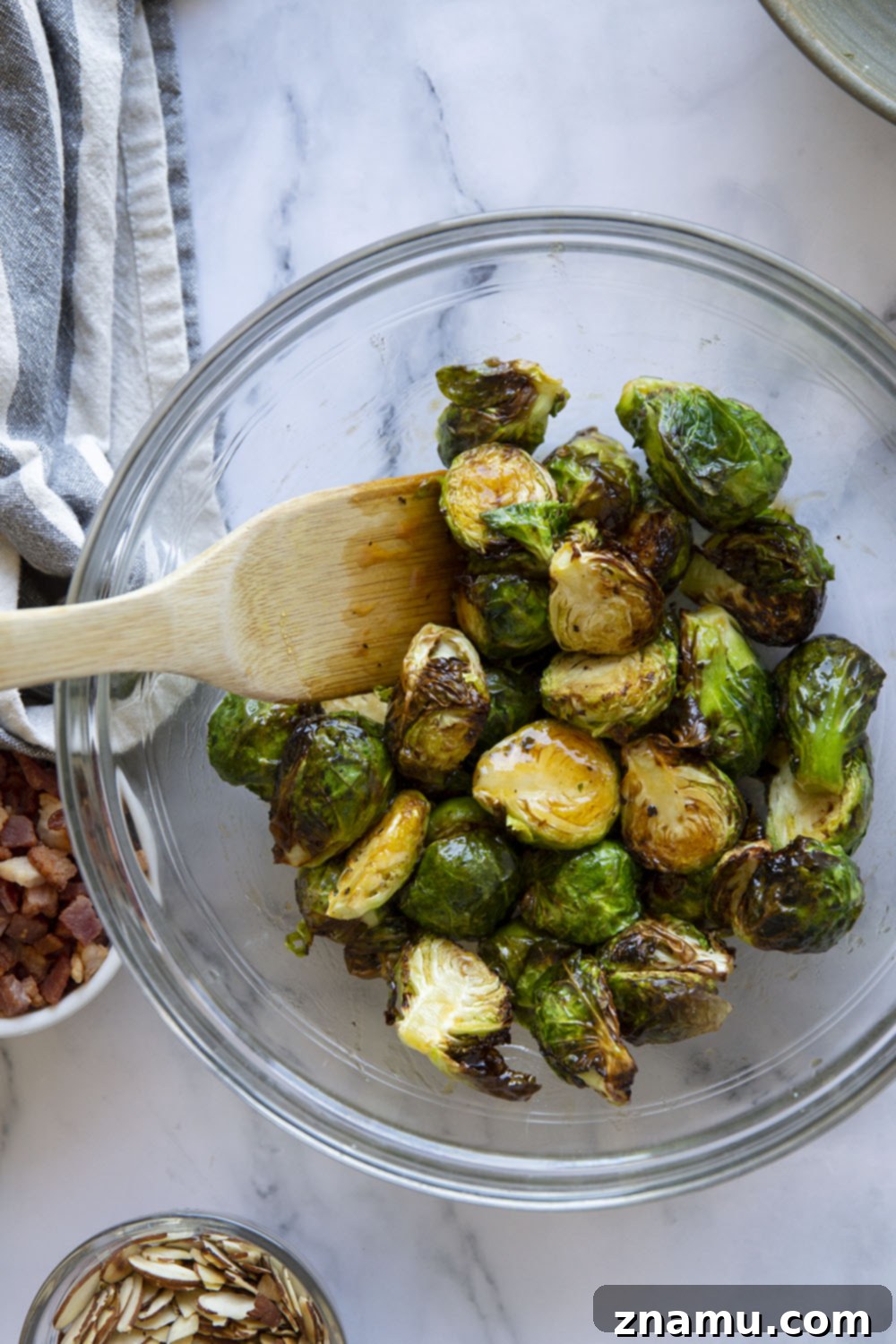 Blistered Air Fryer Brussels Sprouts with Hot Honey Butter 4 Freshly chopped Brussels sprouts being tossed with olive oil, salt, and pepper in a large mixing bowl, ready for the air fryer.