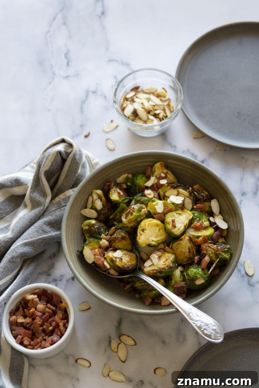 Blistered Air Fryer Brussels Sprouts with Hot Honey Butter 6 A serving bowl filled with glazed air fryer Brussels sprouts, garnished with crumbled bacon and toasted almonds, ready to be served.