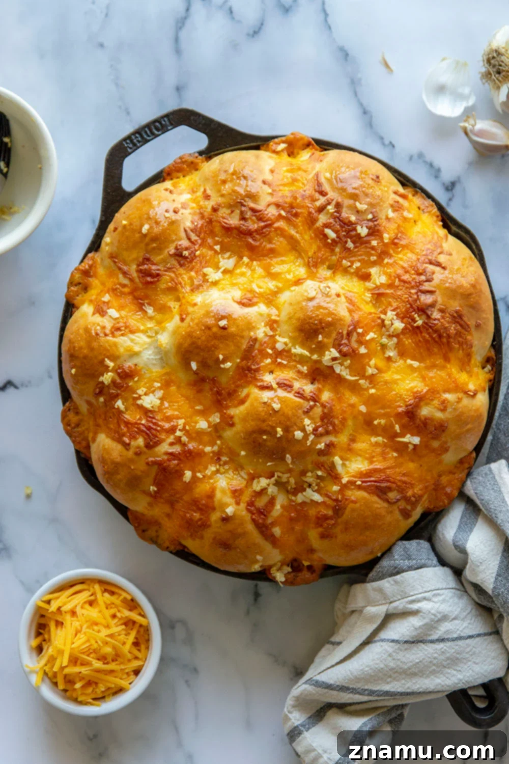 Skillet Garlic Cheddar Dinner Rolls 4 Freshly baked Garlic Cheddar Skillet Dinner Rolls, golden and steaming, in a cast iron skillet.