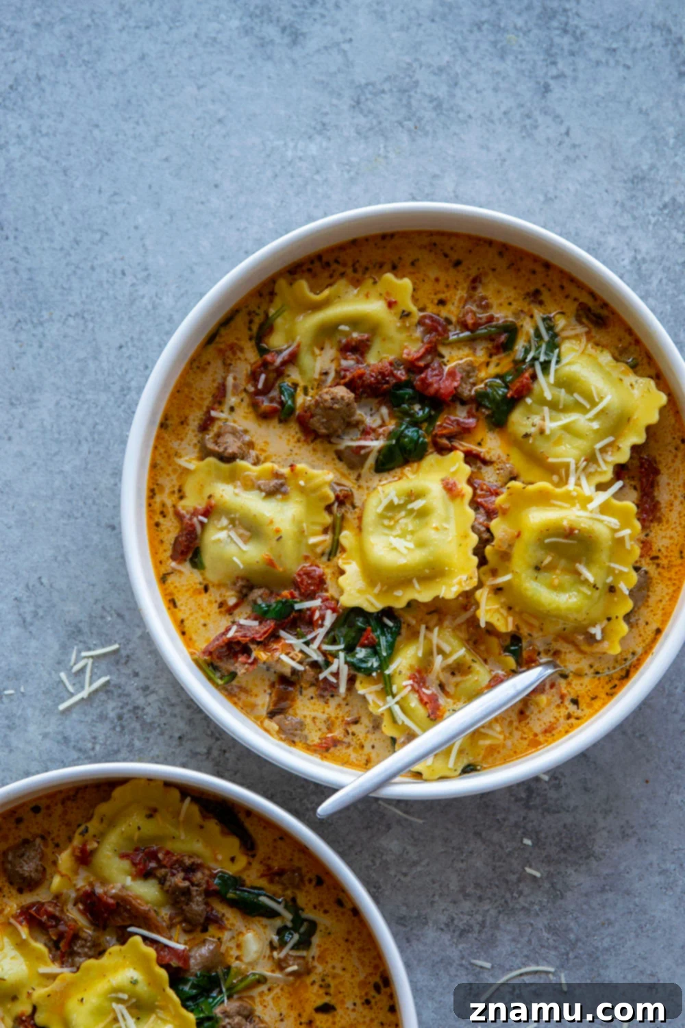 Bowl of Tuscan Ravioli Soup garnished with fresh parsley and Parmesan cheese, ready to be served.