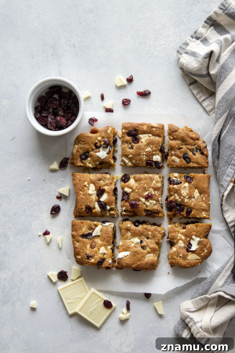 Blissful Cranberry White Chocolate Blondies 5 White chocolate cranberry blondie dough in a baking pan before baking, topped with extra white chocolate chunks and dried cranberries.