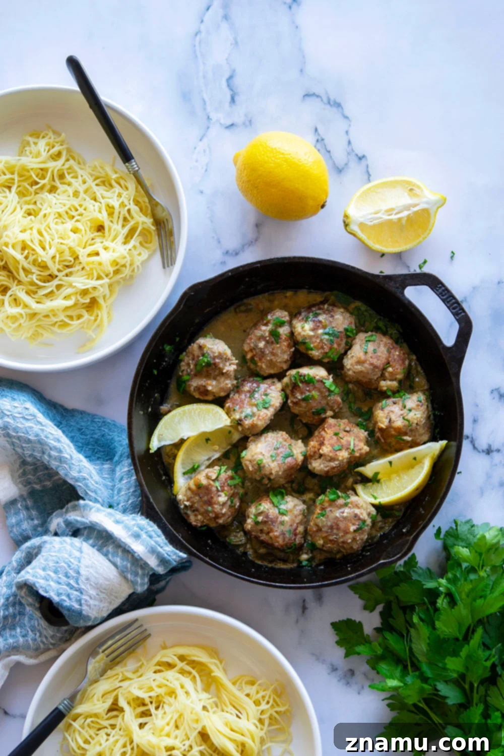 Piccata-Style Chicken Meatballs 3 Close-up of golden brown chicken piccata meatballs cooking in a stainless steel skillet with lemon slices and capers
