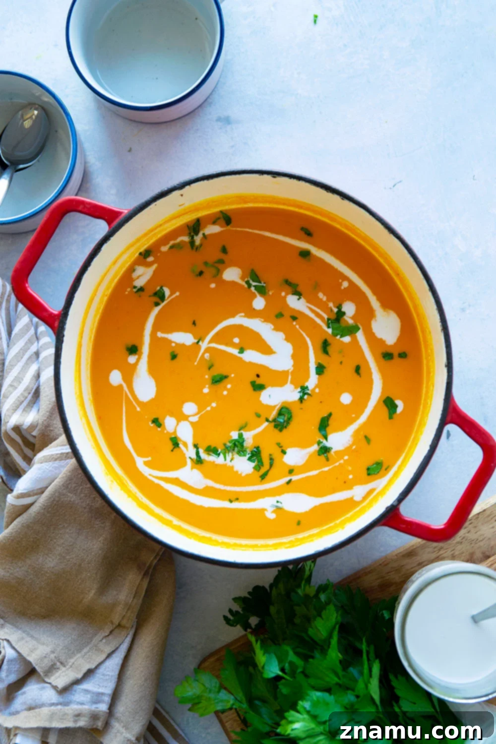 Sweet & Smoky Butternut Squash Soup with Coconut 4 A bowl of creamy butternut squash soup with a drizzle of coconut milk and a sprig of fresh parsley.