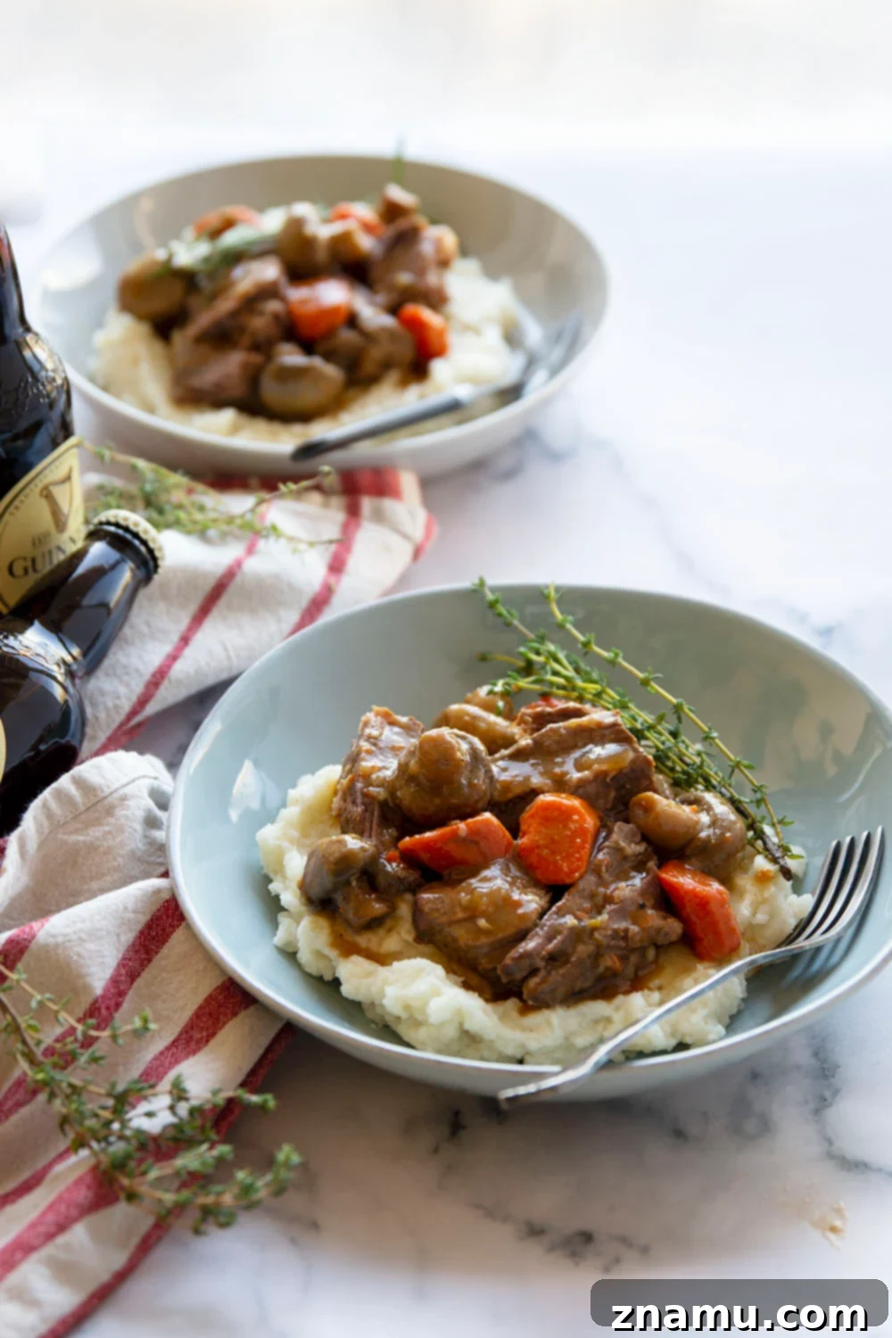 Guinness Braised Beef with Brown Butter Whipped Potatoes 4 Ingredients for Guinness pot roast laid out, including beef chuck roast, carrots, onions, mushrooms, garlic, Guinness beer, beef broth, and fresh herbs.