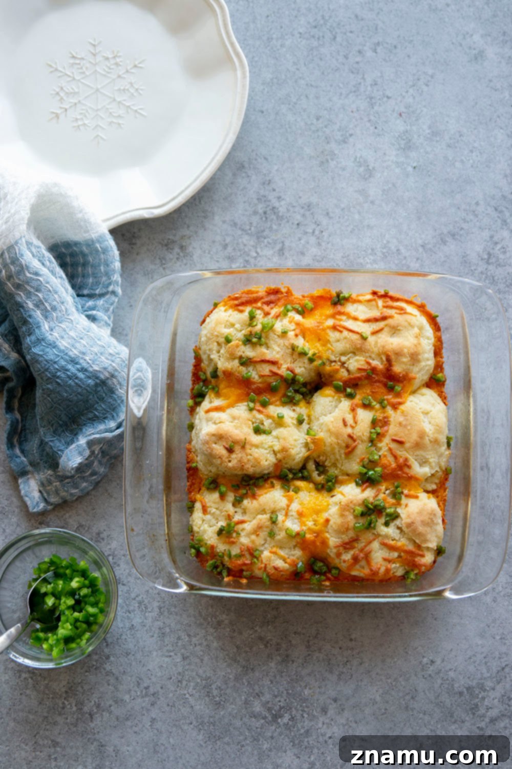 Fluffy Jalapeño Cheddar Pull-Apart Biscuits 5 Hand pulling apart a freshly baked jalapeno cheddar biscuit, revealing melted cheese and flaky layers.