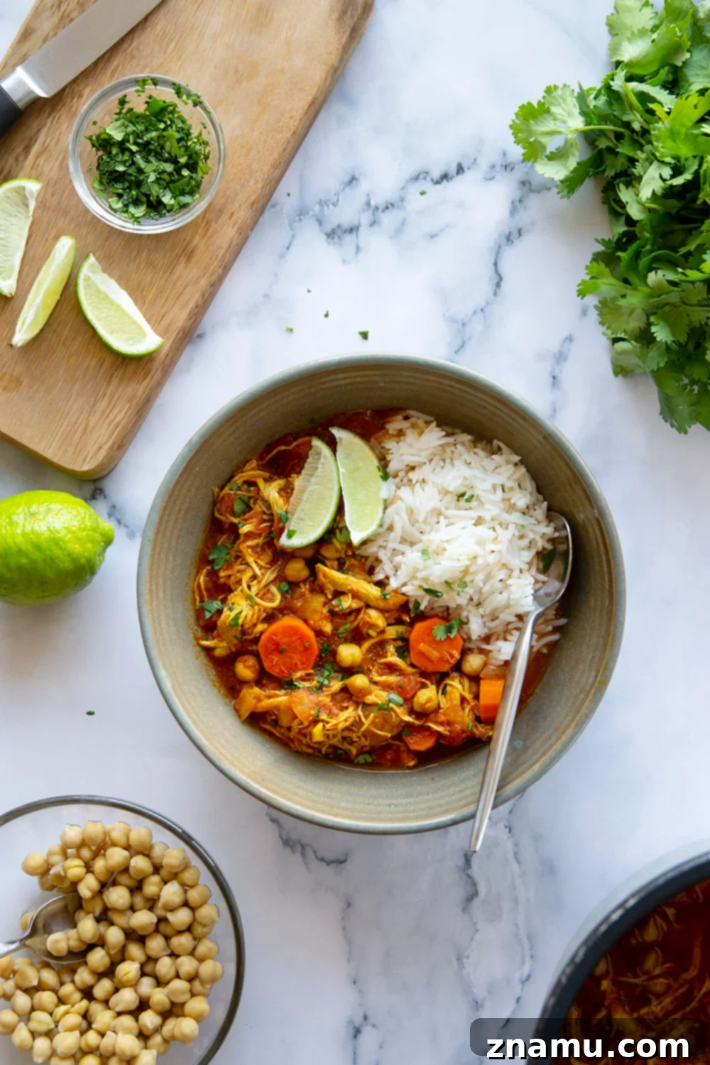 Moroccan Chicken Stew in the Instant Pot 6 A bowl of Instant Pot Moroccan Chicken Stew with steam rising, garnished with fresh herbs and lime.