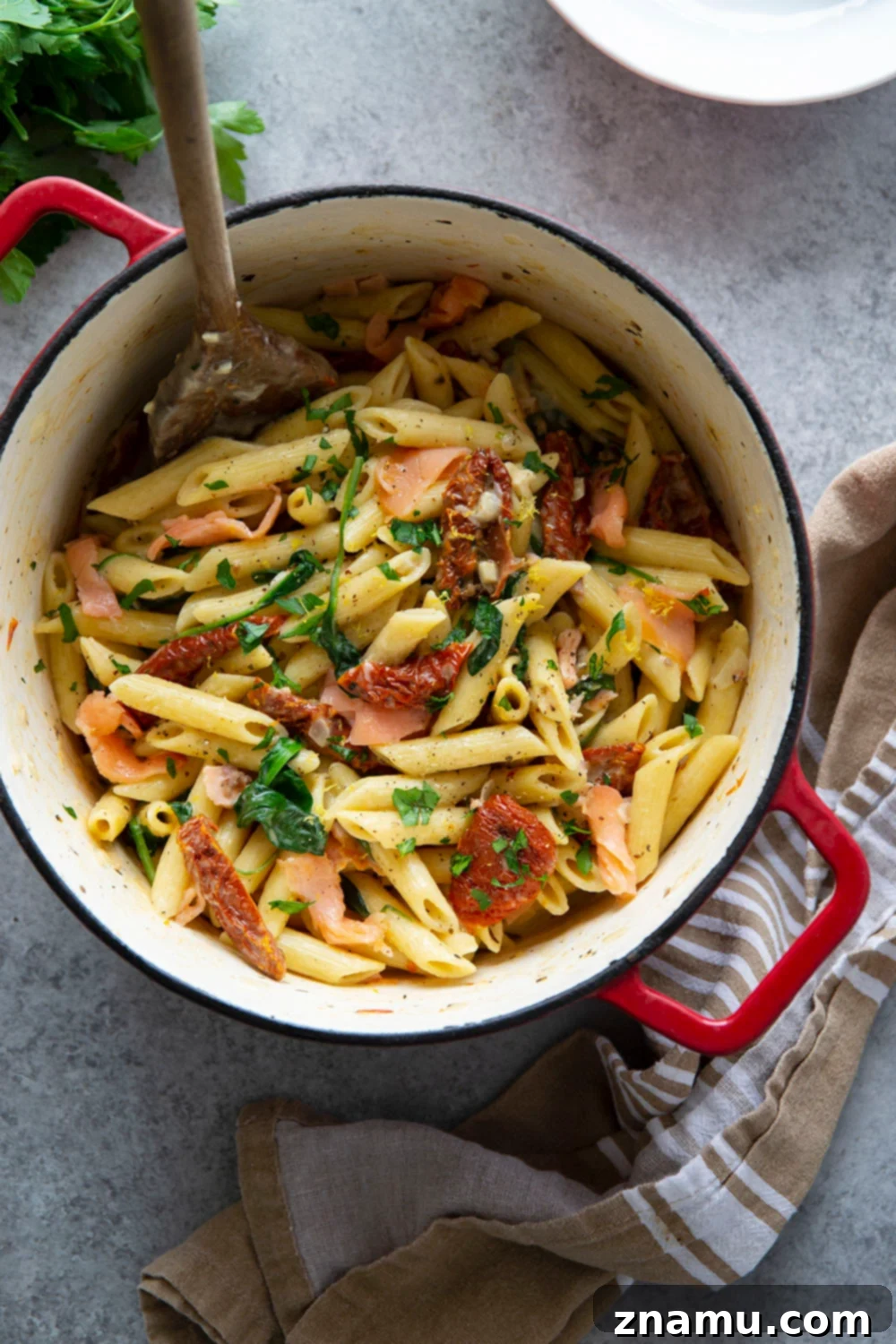 Smoky Salmon Sun-Kissed Tomato Pasta 5 Ingredients for one-pot sun-dried tomato smoked salmon pasta laid out on a wooden surface: raw pasta, fresh spinach, smoked salmon, sun-dried tomatoes, lemon, garlic, and shallot.