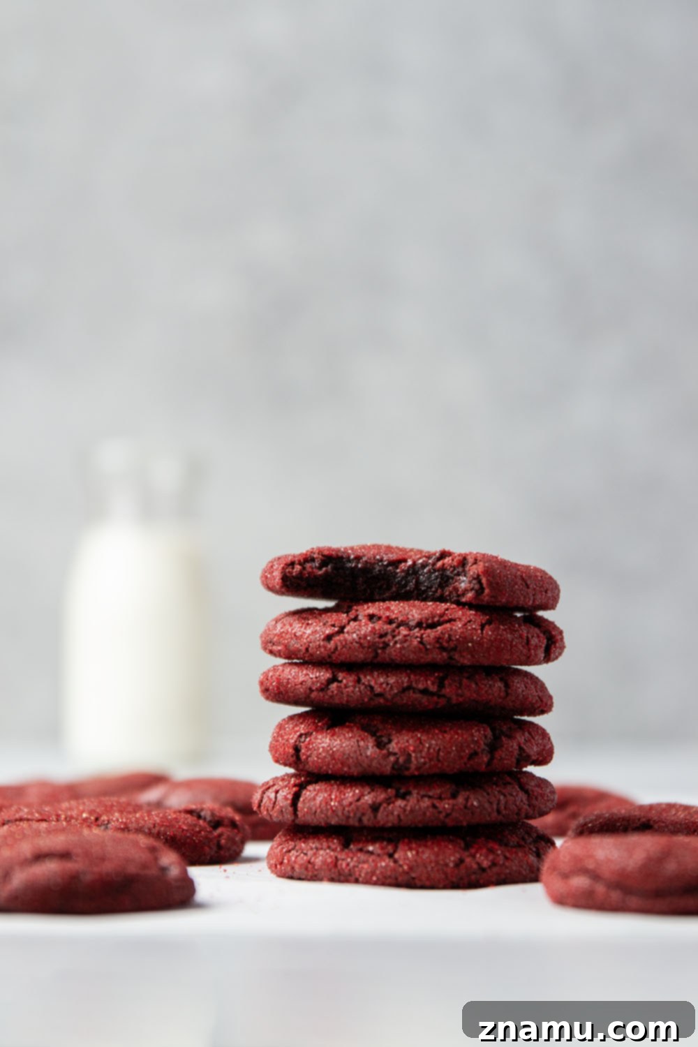 Crimson Velvet Delights 2 Close-up of a perfectly baked, fudgy red velvet cookie rolled in sparkling red sugar, showcasing its vibrant color and cracked top.