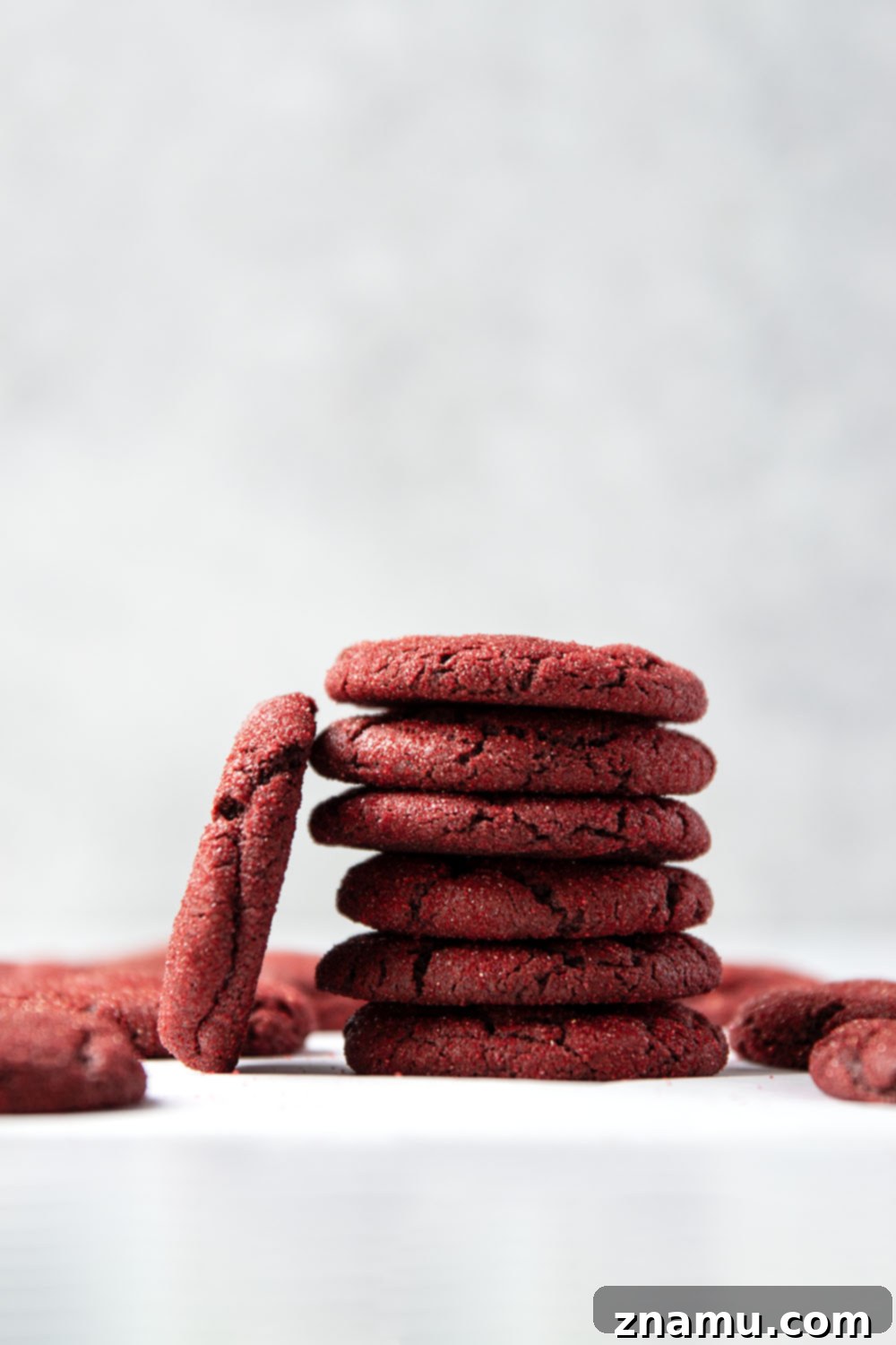 Crimson Velvet Delights 3 A stack of freshly baked red velvet cookies dusted with red sanding sugar, highlighting their soft texture and festive appearance.