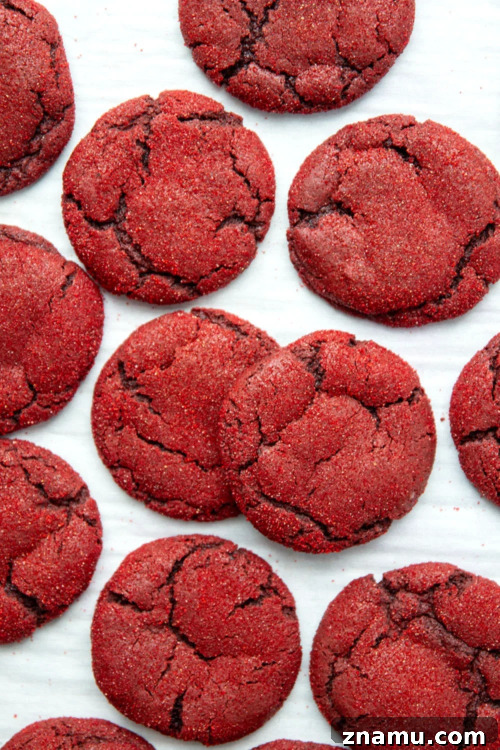 Crimson Velvet Delights 4 A close-up shot of a single red velvet cookie, showcasing its sparkly top and soft, cracked texture.