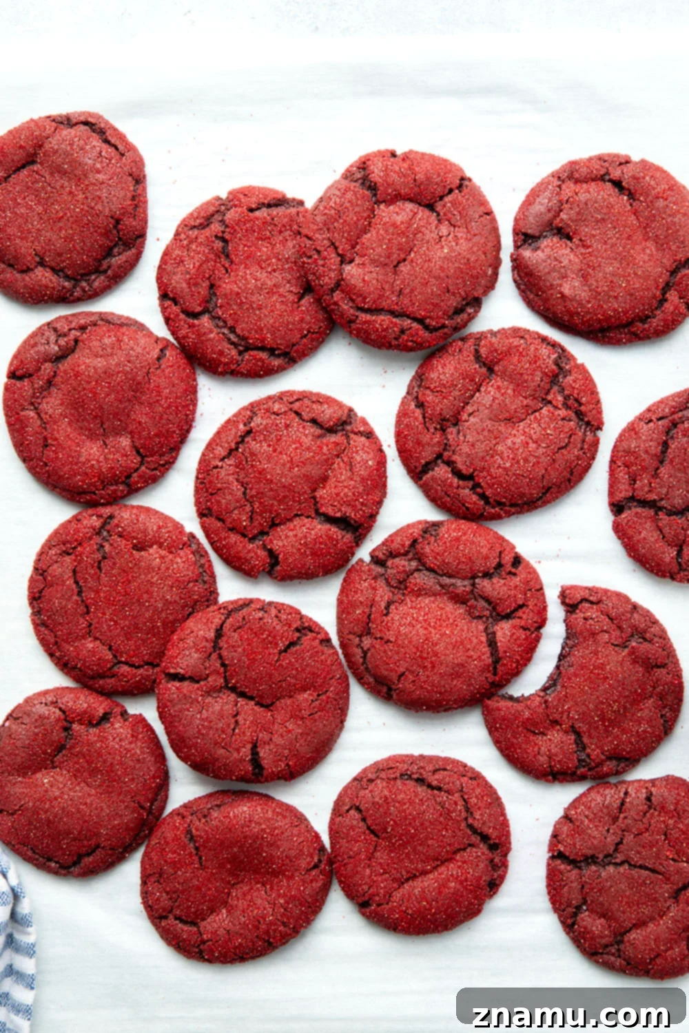 Crimson Velvet Delights 5 An overhead shot of red velvet cookie dough balls rolled in red sanding sugar, ready for baking on a parchment-lined sheet.