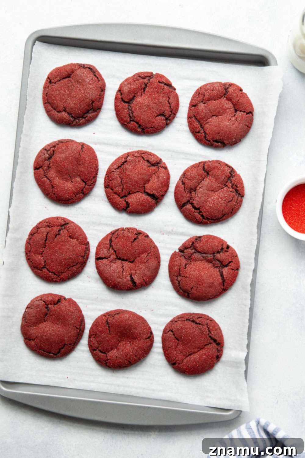Crimson Velvet Delights 6 A top-down view of several baked red velvet cookies on a white plate, emphasizing their uniform shape and vibrant red color.