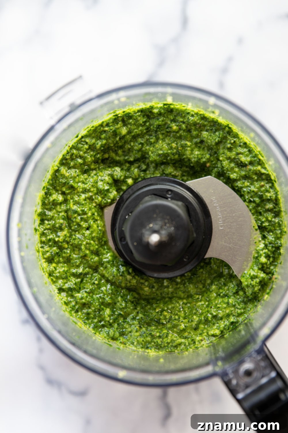 Emerald Spinach Basil Pesto 4 Ingredients for spinach basil pesto laid out on a wooden board, including fresh basil, spinach, pine nuts, garlic, and Parmesan cheese.