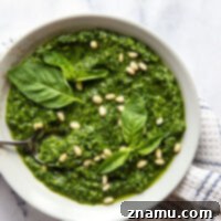 A small image of spinach basil pesto in a bowl with basil leaves.