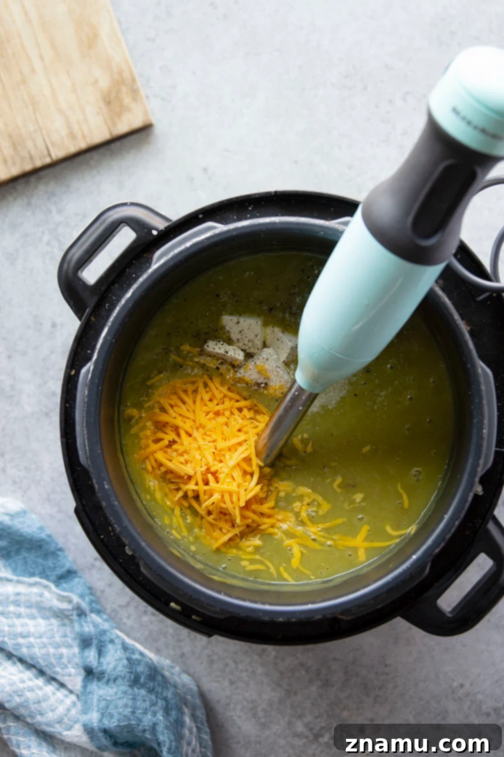 Ingredients for Instant Pot Potato Leek Soup laid out on a cutting board, including leeks, potatoes, garlic, and butter.