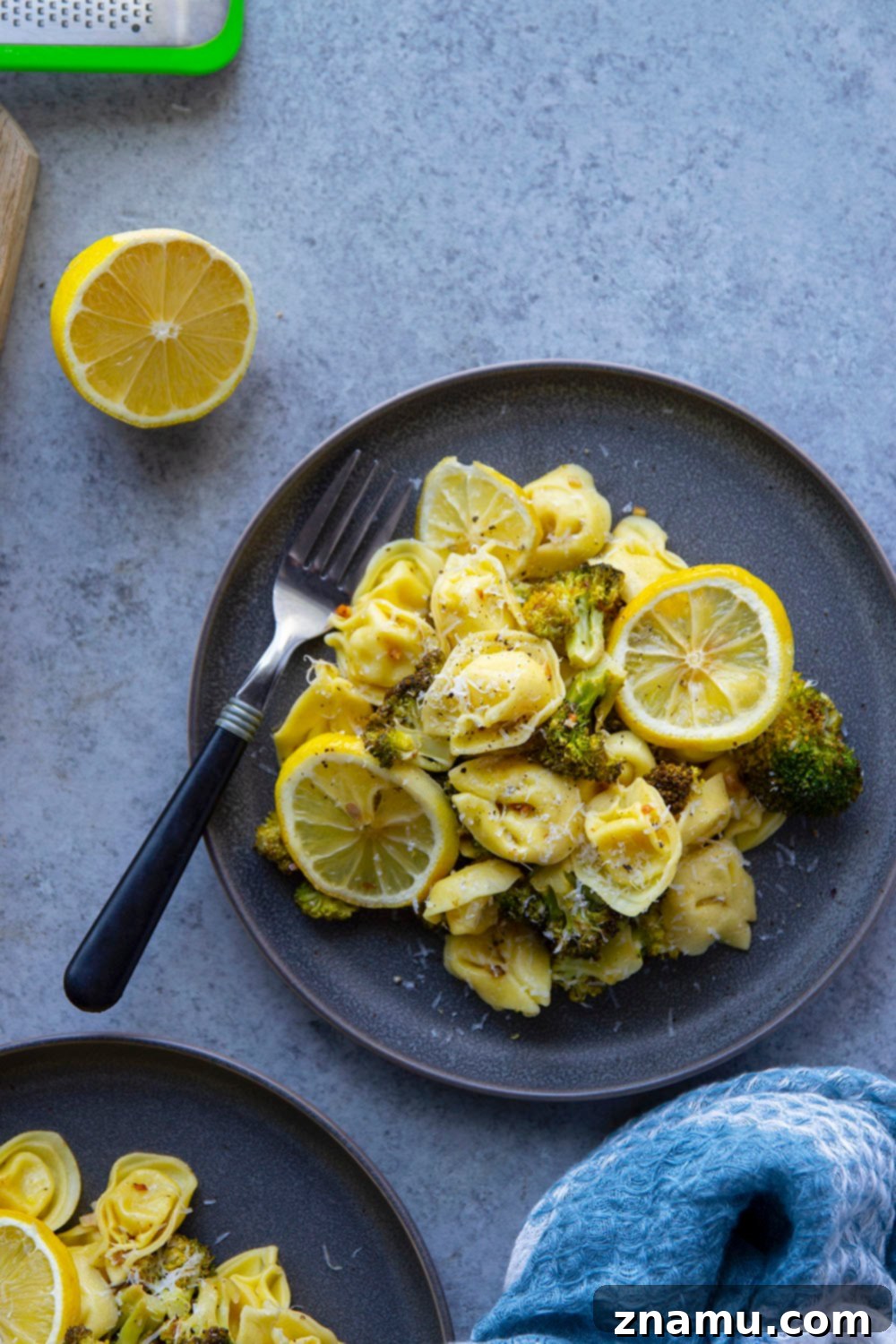 Zesty Roasted Broccoli Tortellini 6 A serving of Lemon Roasted Broccoli Tortellini in a white bowl, garnished with fresh lemon zest and parsley, ready to be enjoyed.