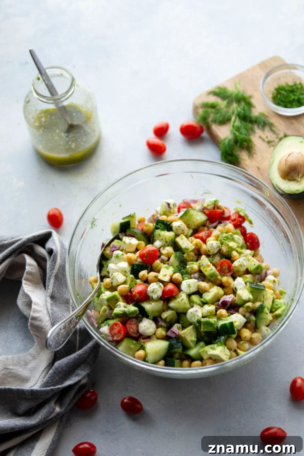 Creamy Italian Avocado Chickpea Salad 3 Close-up of a bowl of Italian Avocado Chickpea Salad, highlighting the fresh, colorful ingredients like halved cherry tomatoes, green cucumber, and white mozzarella pearls, with tender chickpeas and creamy avocado visible.