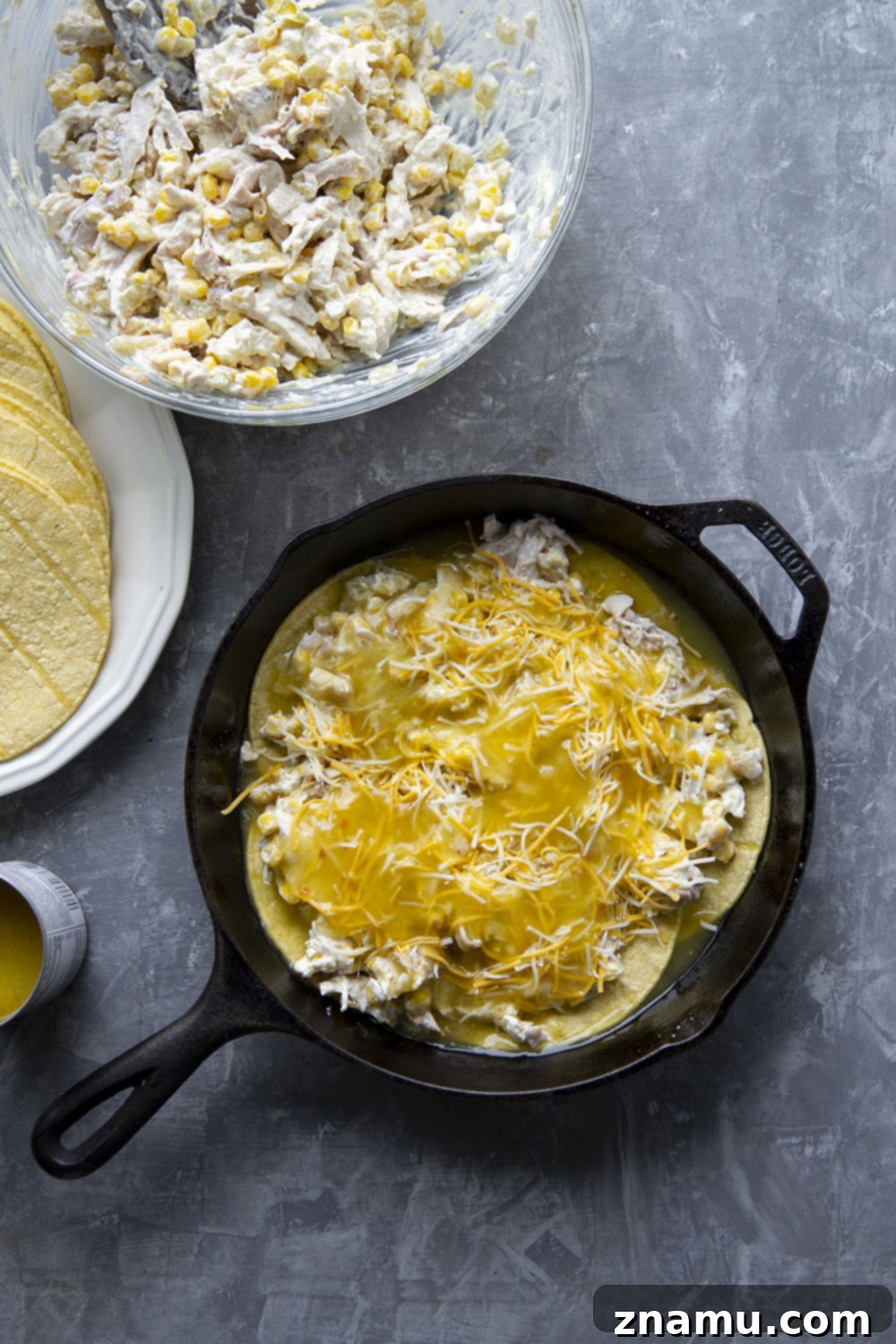 Essential ingredients for green chile chicken enchilada casserole, including shredded chicken, vibrant green chiles, sweet corn, and rich cheese, neatly arranged on a counter.