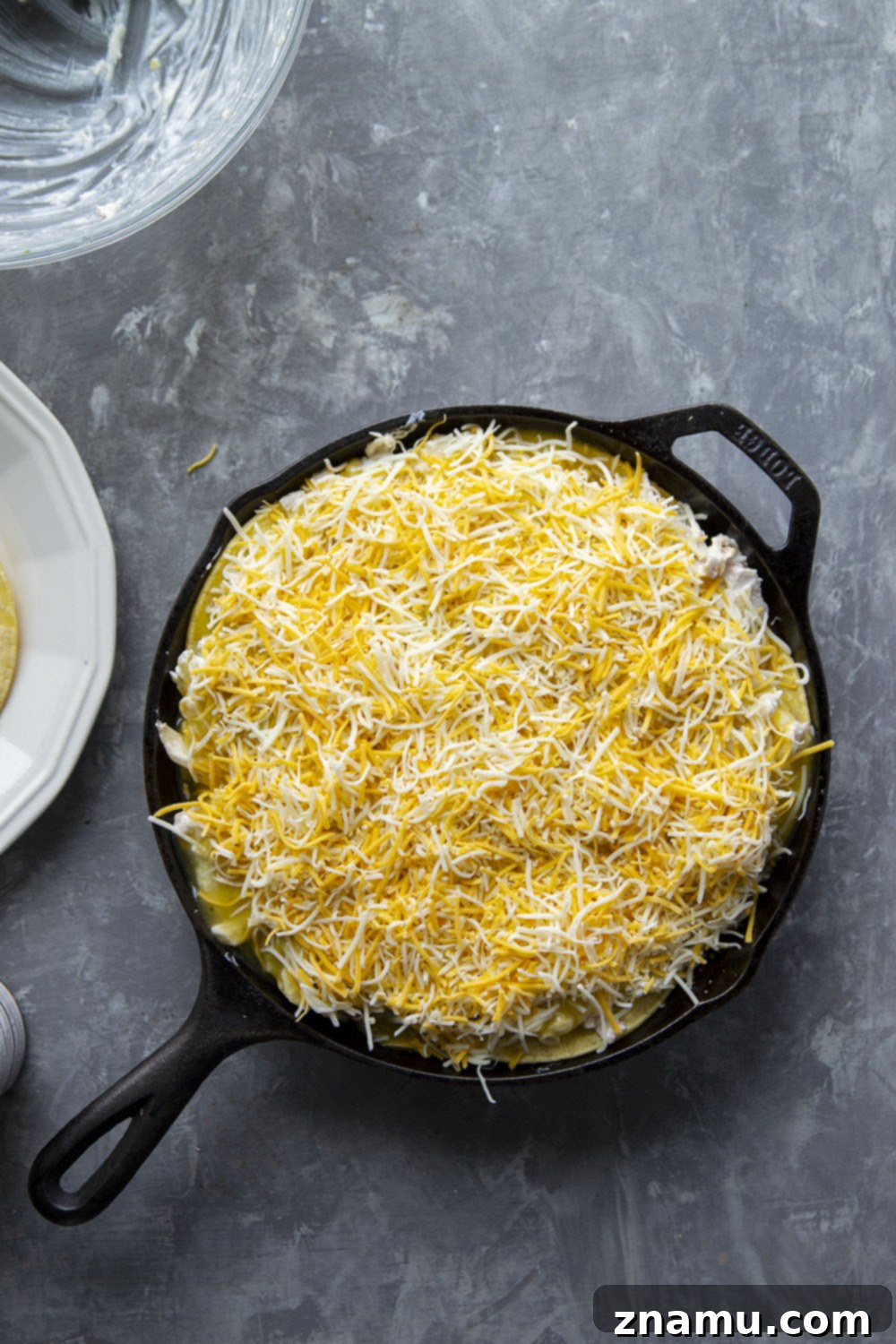 A beautifully golden-brown and bubbling skillet green chile chicken enchilada casserole, fresh out of the oven and garnished with cilantro, ready to be enjoyed.