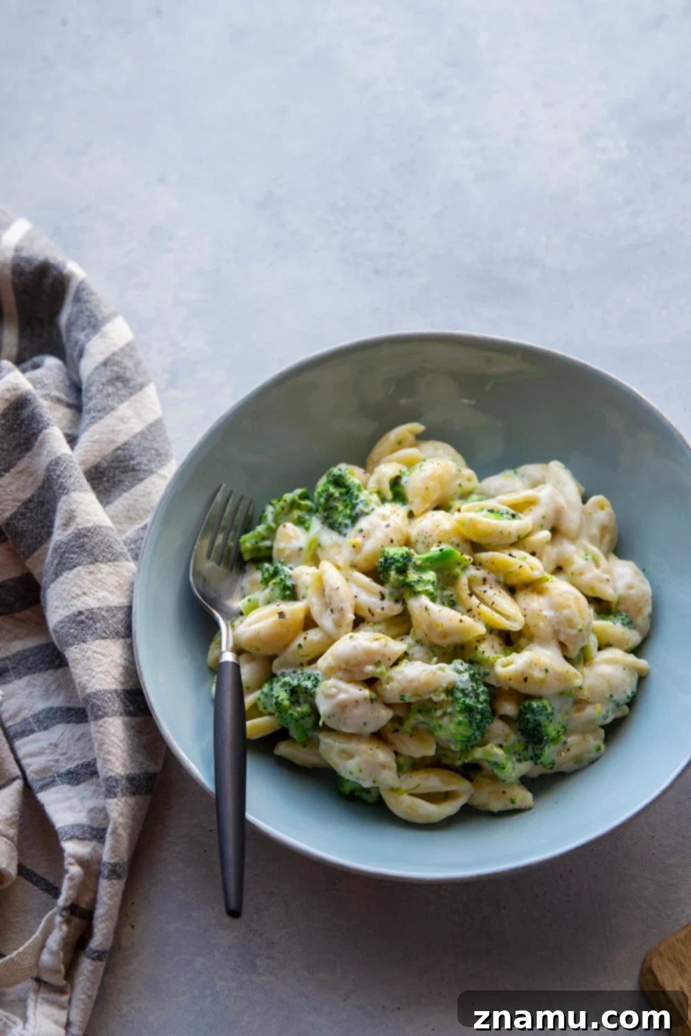 Creamy White Cheddar Broccoli Shells 5 A bowl of White Cheddar Broccoli and Shells, with a spoon digging into the creamy pasta.