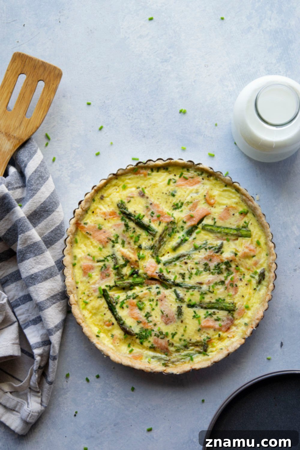 Close-up of a slice of Asparagus Smoked Salmon Quiche, highlighting the flaky crust and vibrant filling.