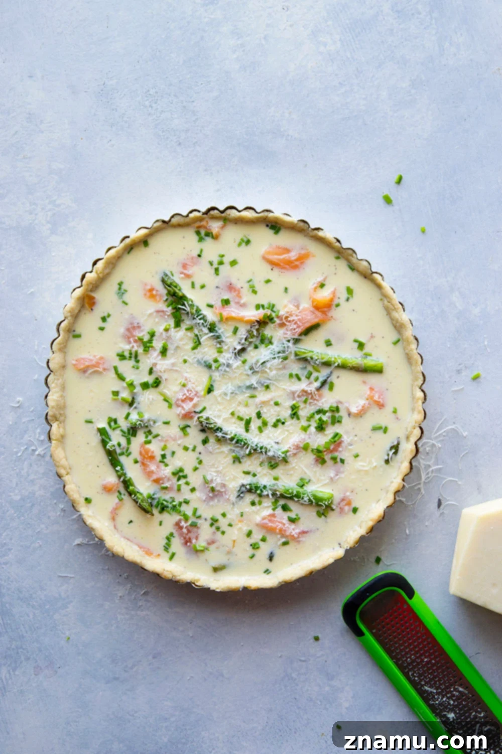 Asparagus Smoked Salmon Quiche baking in a tart pan, showcasing the golden crust and bubbling filling.