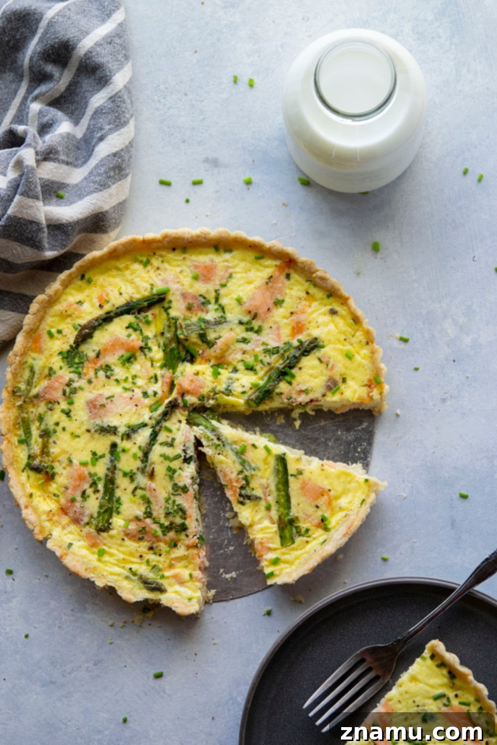 Freshly baked Asparagus Smoked Salmon Quiche, sliced and ready to serve on a brunch table.