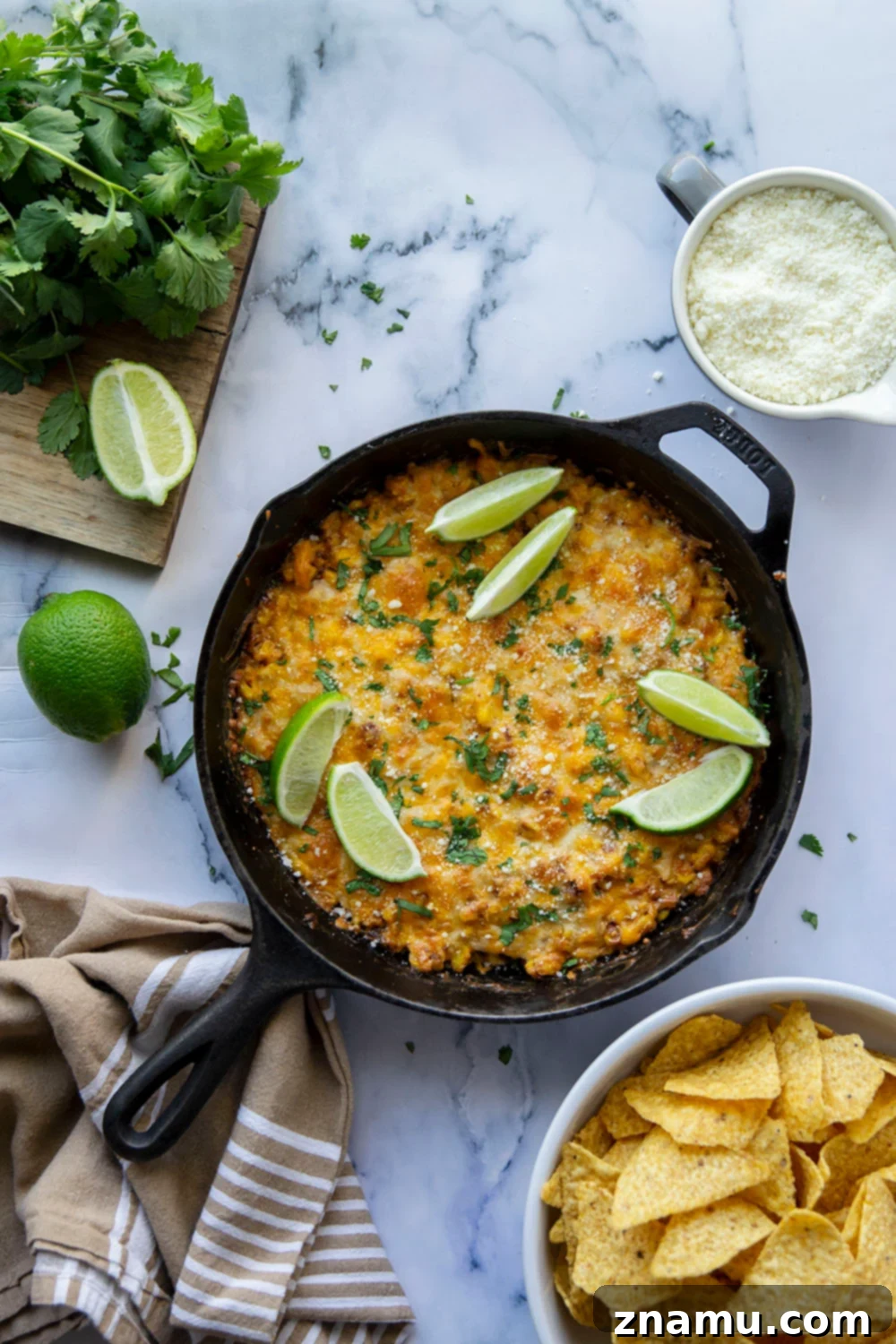 Smoky Chipotle Elote Dip 3 A large cast iron skillet filled with bubbling Chipotle Mexican Street Corn Dip, showcasing the golden-brown melted cheese and hints of charred corn underneath.