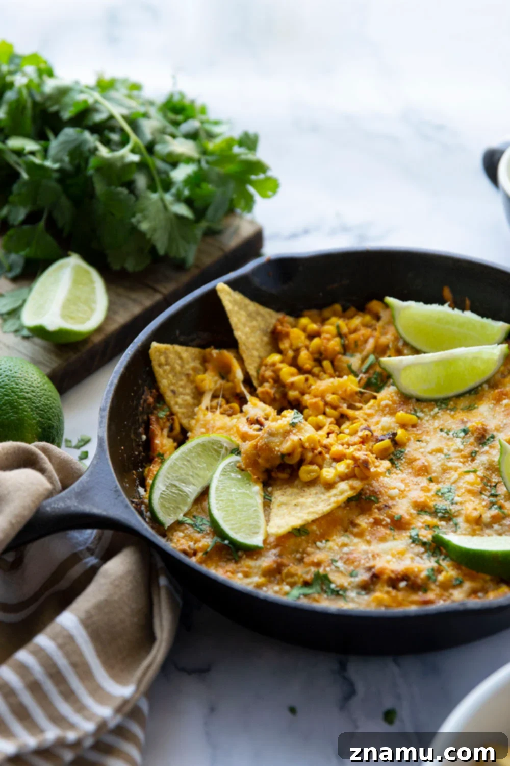 Smoky Chipotle Elote Dip 4 A close-up view of the creamy, golden Chipotle Mexican Street Corn Dip, garnished with fresh green cilantro and bright lime wedges.