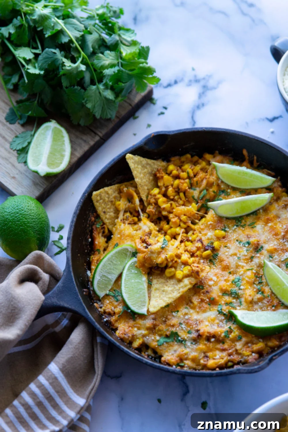 Smoky Chipotle Elote Dip 6 A generous serving of Chipotle Mexican Street Corn Dip with a spoon scooping out a portion, surrounded by crispy tortilla chips on a rustic wooden surface.
