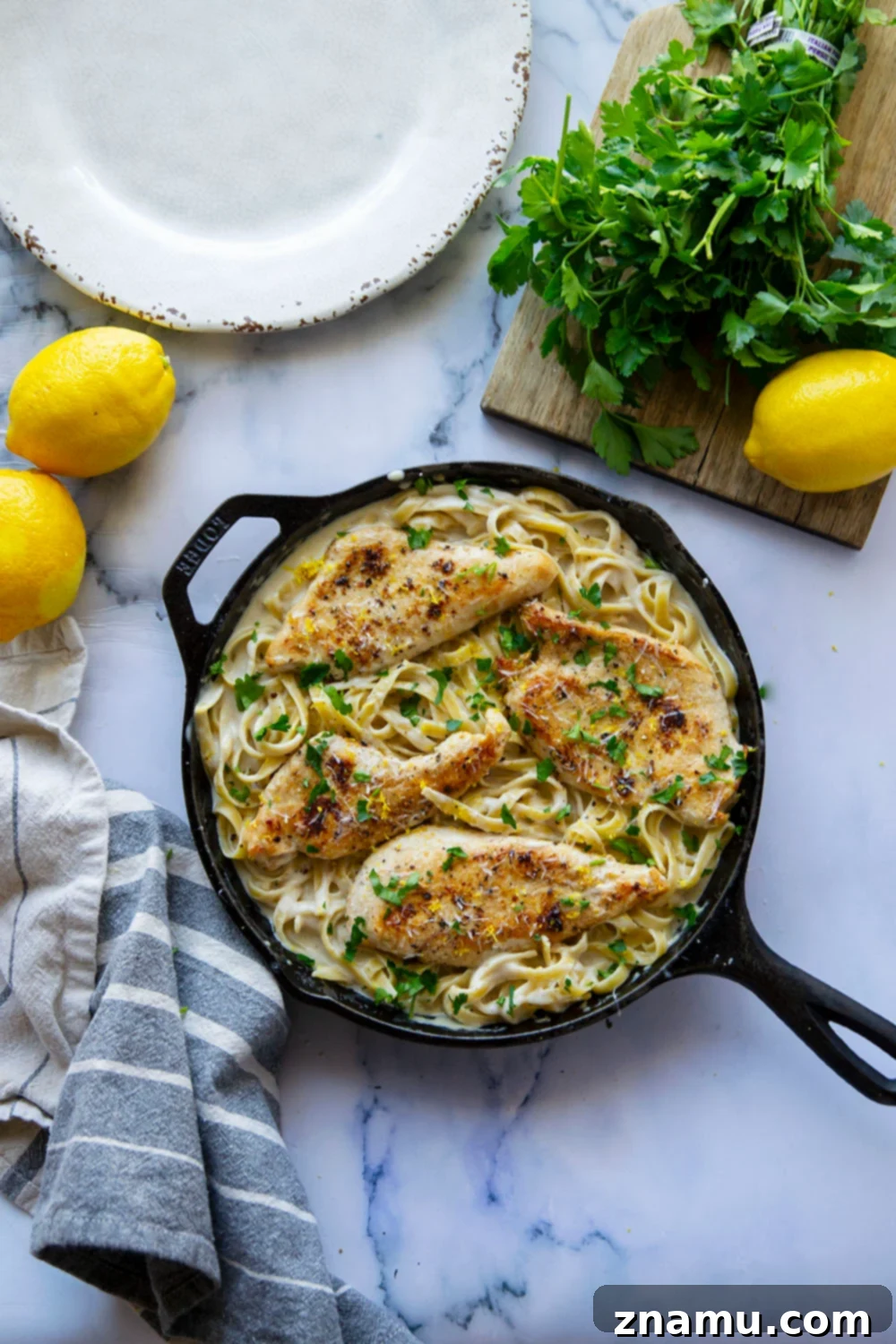 Creamy Lemon Pepper Chicken Alfredo Fettuccine 4 Serving of lemon pepper chicken alfredo fettuccine garnished with fresh herbs.