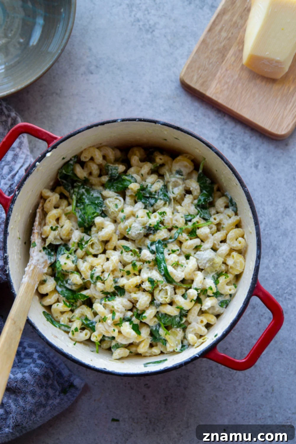 Effortless One-Pot Spinach Artichoke Pasta 4 Ingredients for One-Pot Spinach Artichoke Pasta laid out on a cutting board.