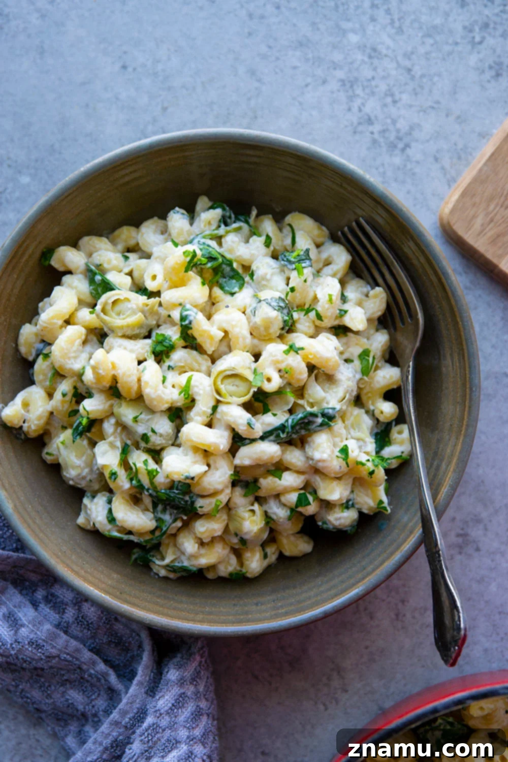 Effortless One-Pot Spinach Artichoke Pasta 5 A serving of One-Pot Spinach Artichoke Pasta garnished with fresh parsley.