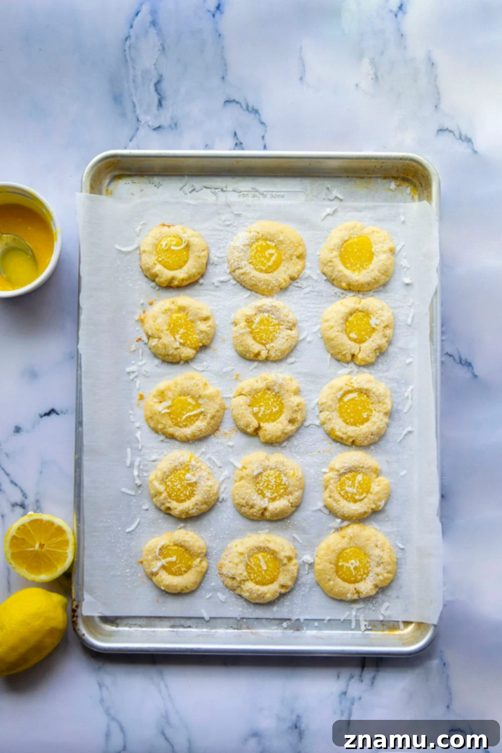 Coconut Lemon Curd Thumbprints 4 A close-up view of the tender, golden-brown shortbread cookie dough being pressed to form the thumbprint indentation.