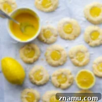 These lemon curd thumbprint cookies feature a buttery coconut shortbread cookie filled with tangy homemade lemon curd. - a pretty addition to any cookie tray!