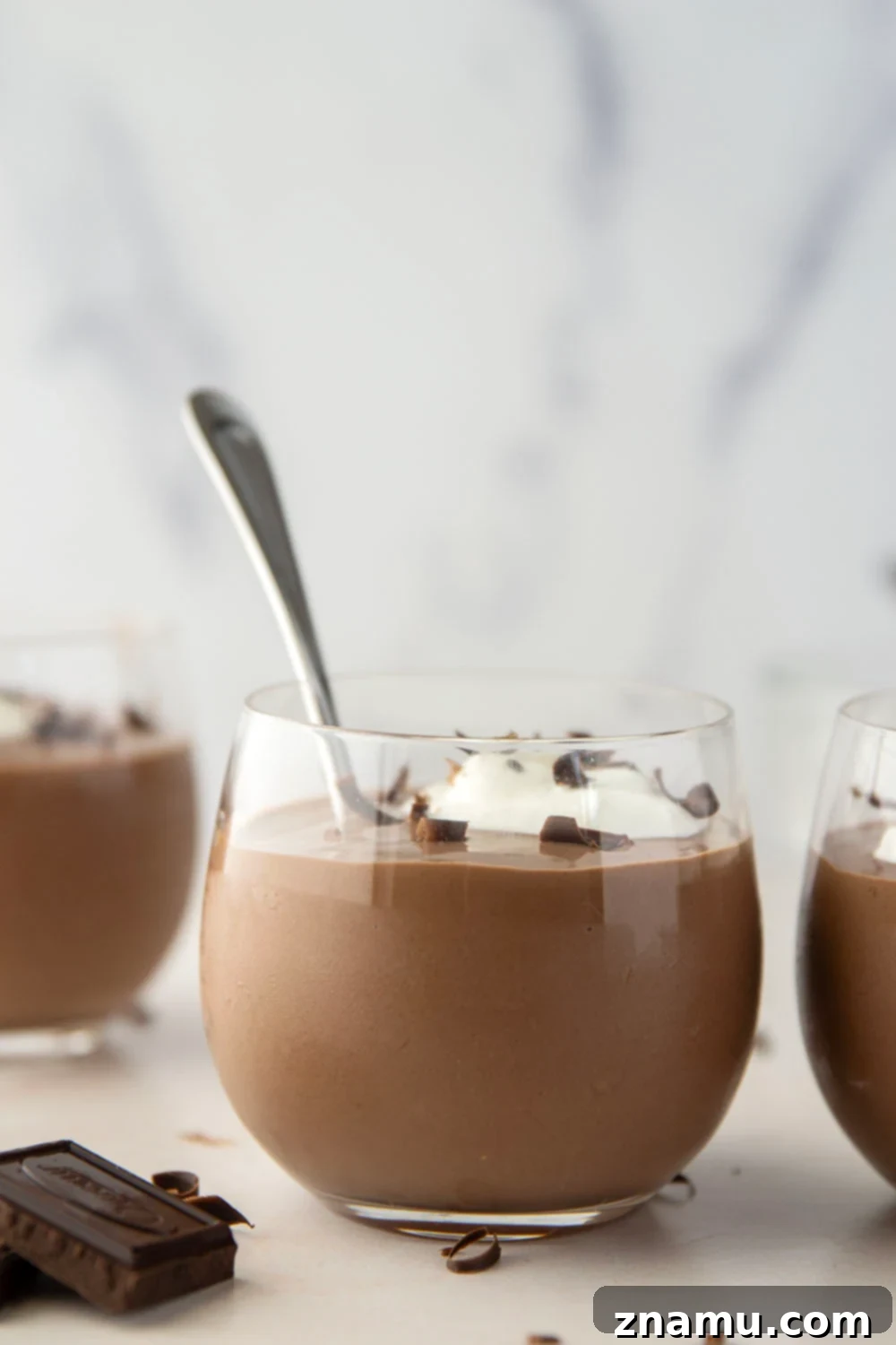 Velvety Homemade Chocolate Pudding 4 A bowl of chocolate pudding with a spoon dipped in, showcasing its thick, creamy consistency.