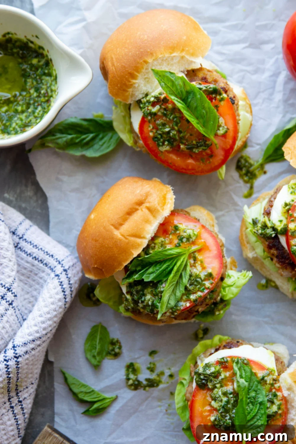 These Caprese Chicken Burgers are perfectly juicy and dressed up with all the caprese fixings and a flavorful pesto vinaigrette drizzled on top.