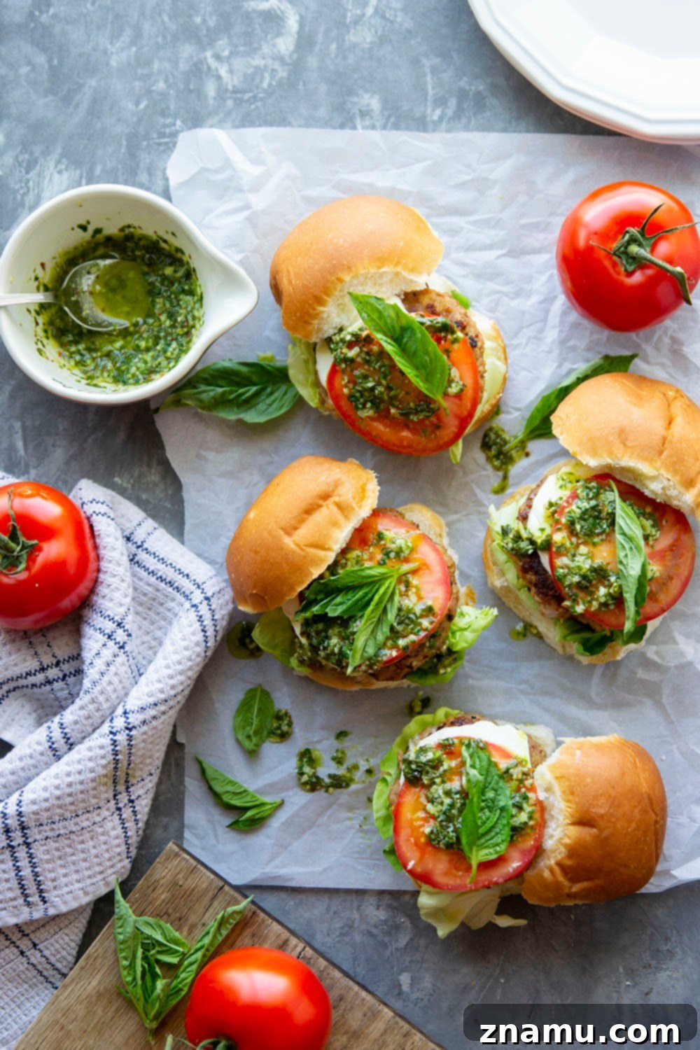 These Caprese Chicken Burgers are perfectly juicy and dressed up with all the caprese fixings and a flavorful pesto vinaigrette drizzled on top.